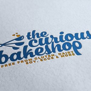 a logo design embossed into white paper reads "the curious bakeshop"