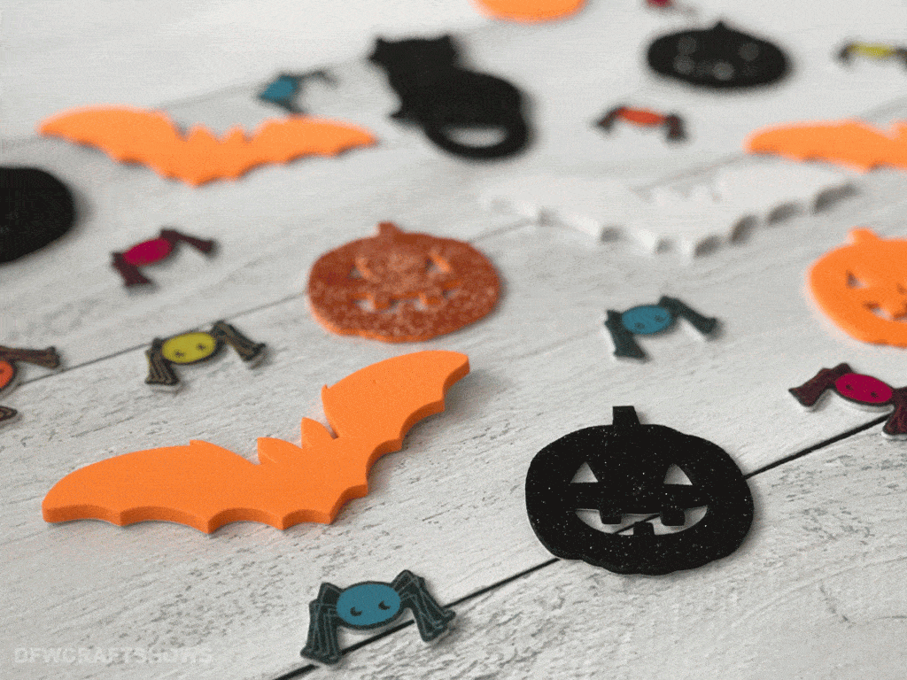 An assortment of orange, white, and black halloween themed stickers lays on a wooden table