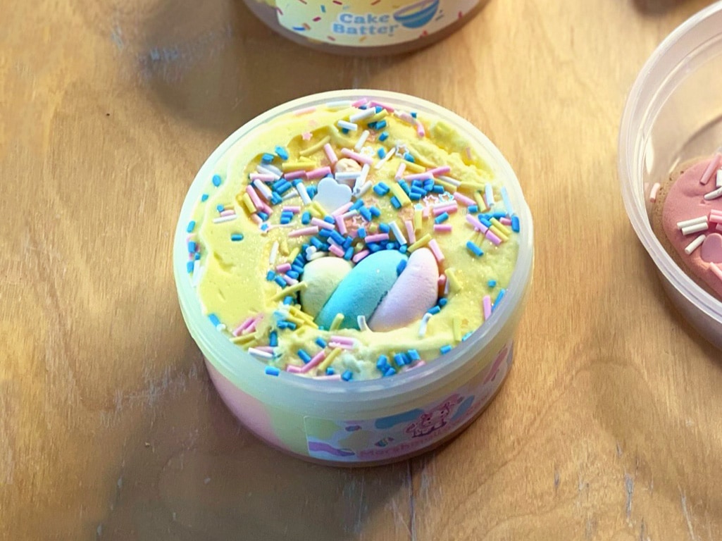 Marshmallow cow slime by peachybbies is yellow with rainbow sprinkles and a little marshmallow toy