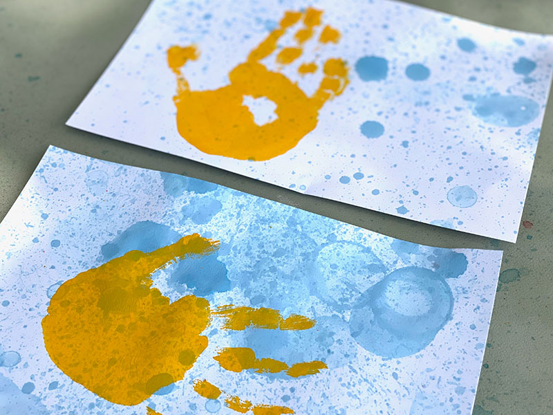 Bubble paint art with yellow handprints added