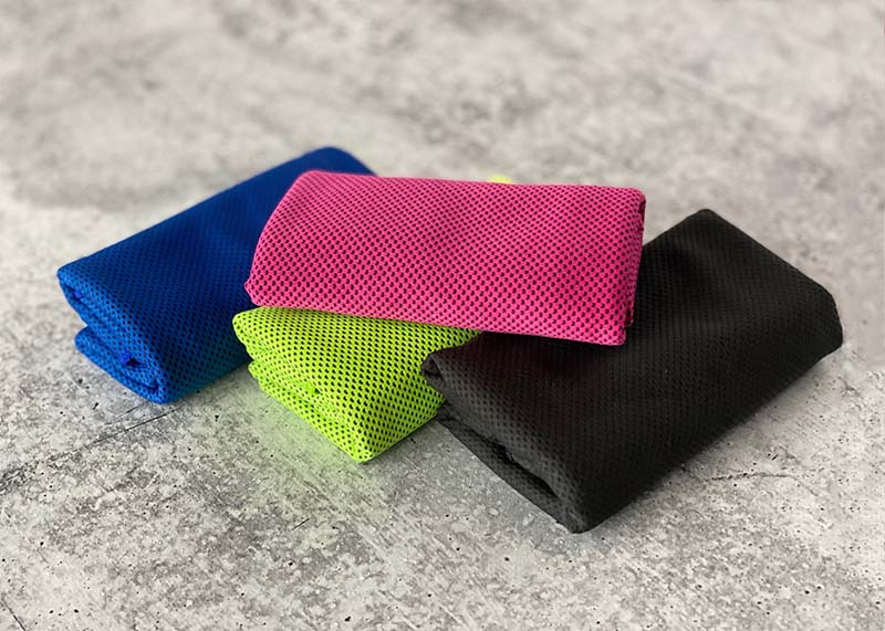 a stack of 4 colorful cooling towels rest on the concrete