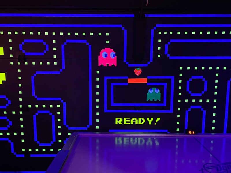 a black light lit arcade room with pac man designs on the wall