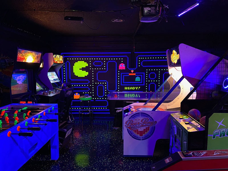 A blacklight lit arcade room full of games