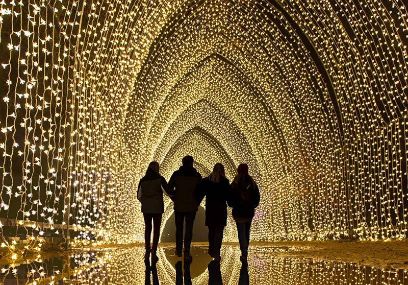several people walking through a tunnel made of lights