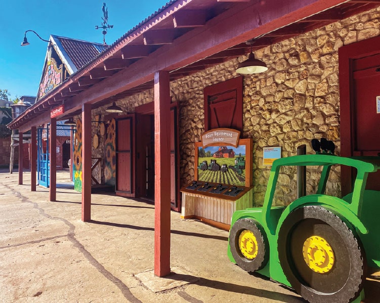 Buildings and storefronts at the Texas Wild! at the Fort Worth Zoo.  A grren tractor cutout can be seen out front. 