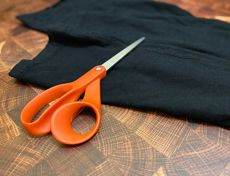 a pair of cut leggings sits beneath a pair of orange handled fiskars scissors