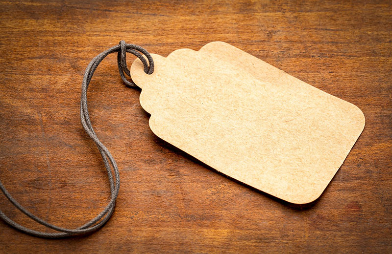 a blank, beige tag with twine is spread across a wooden table