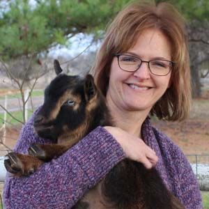 Picture of Julie, a woman in purple holding a goat