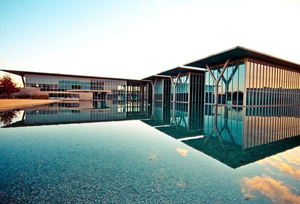 A building covered in windows and glass next to a large reflecting pool
