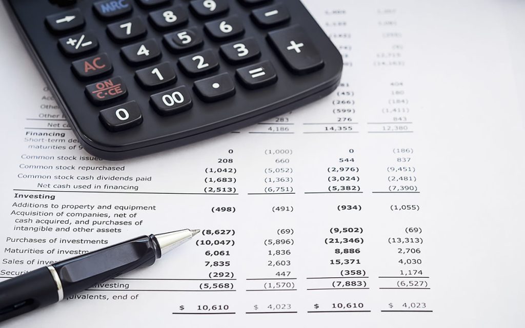 An income statement lays on a desk beneath a calculator and pen