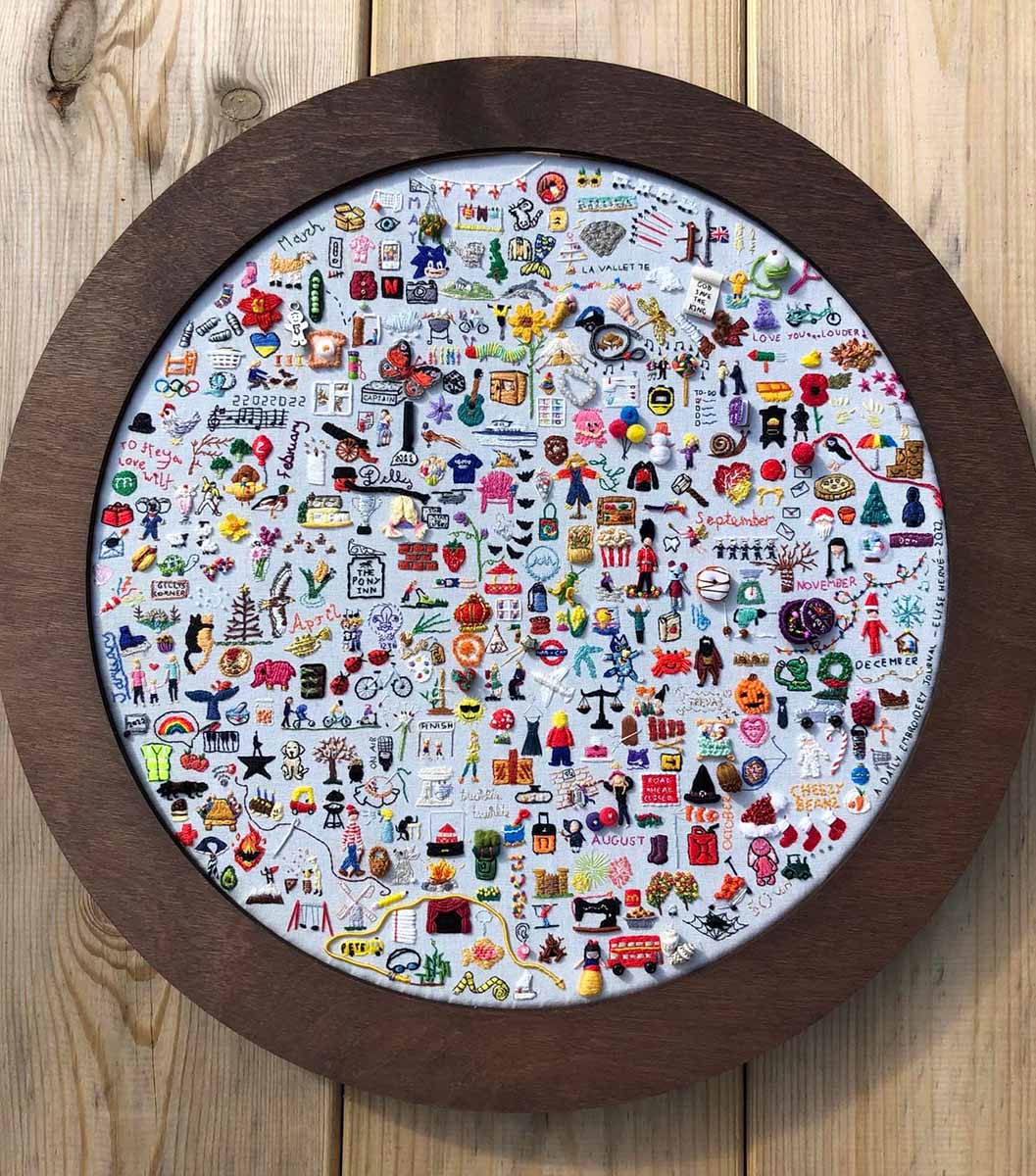 A finished Embroidery journal is featured in a gorgeous round, wooden frame without glass
