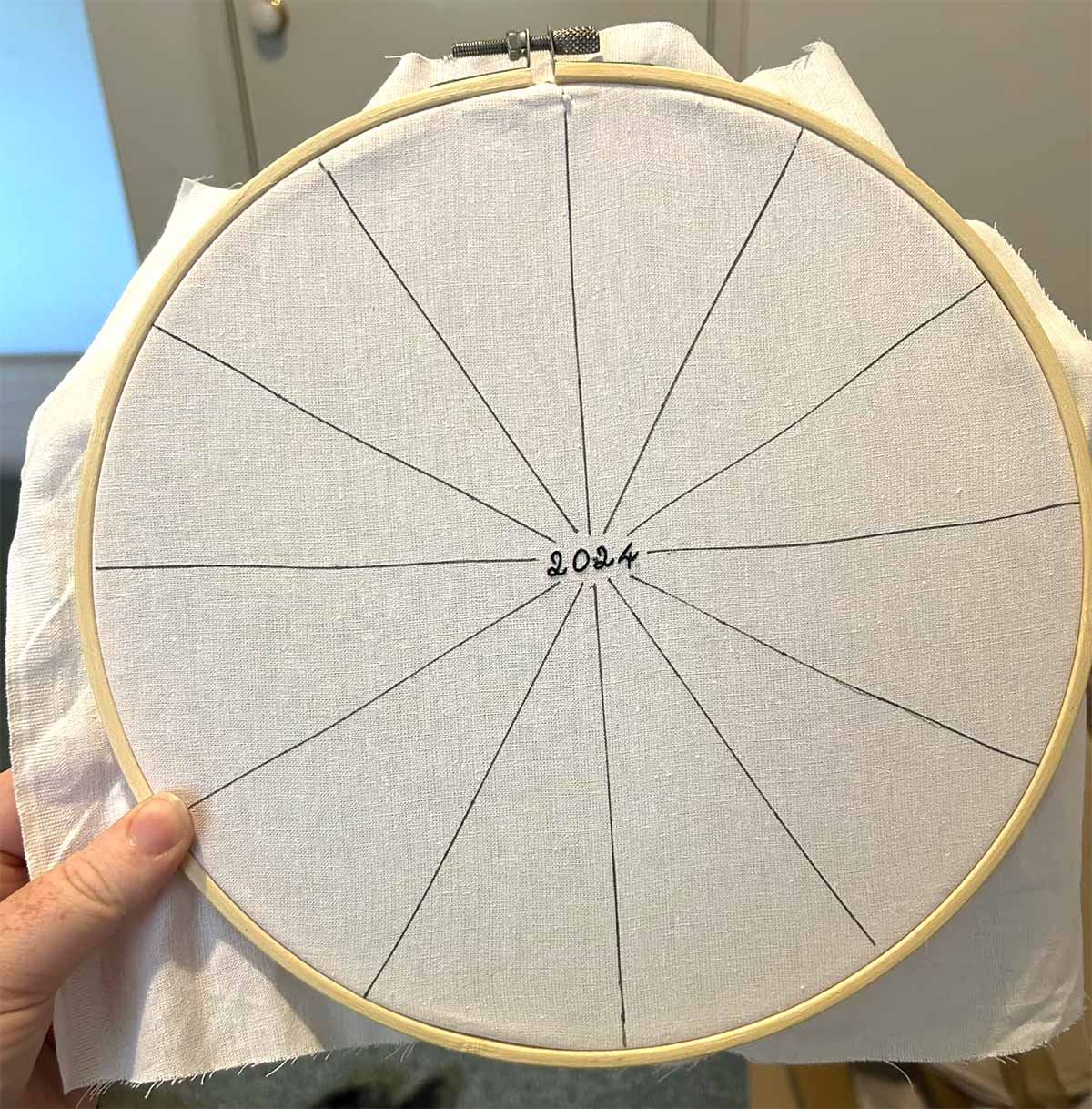Lines are traced onto an embroidery hoop with the text "2024" stitched in the middle. Everything else is blank.