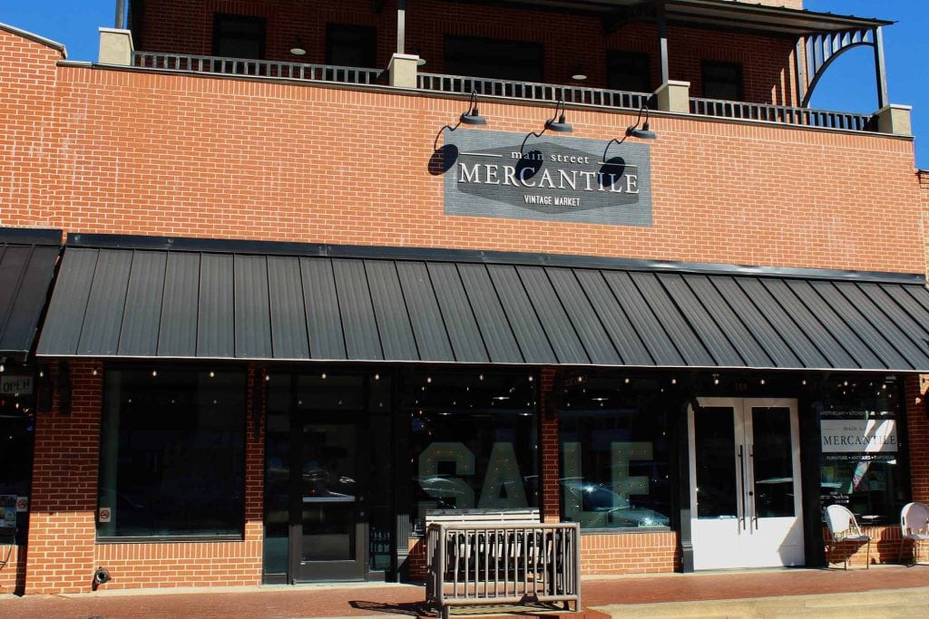 reddish orange brick building with a black awning and signage that reads main street mercantile