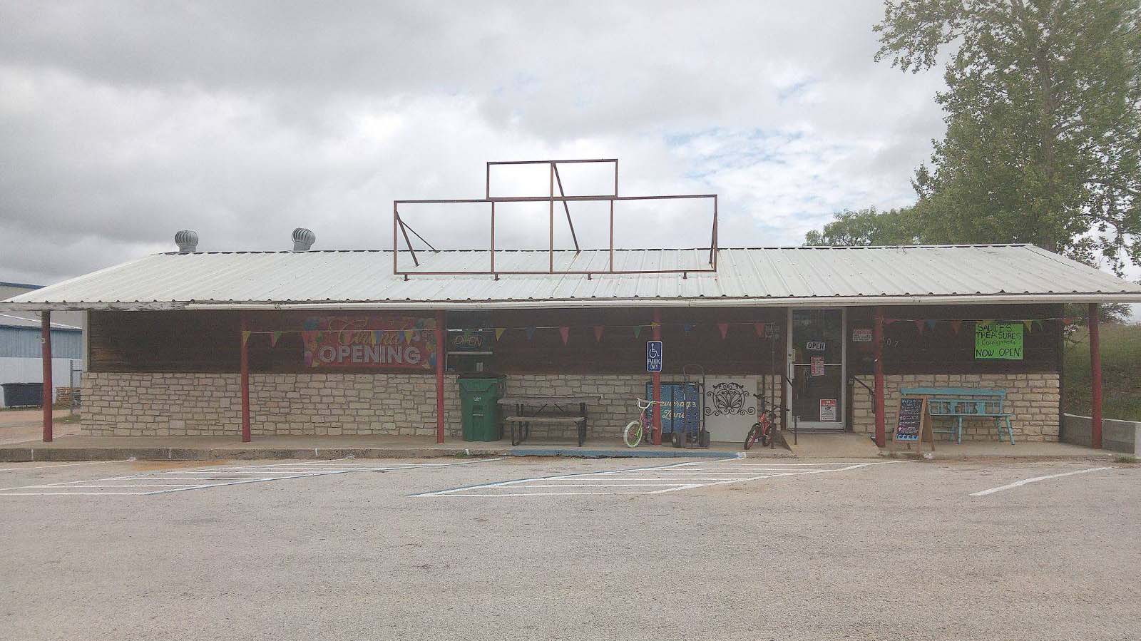 Dark brown building with tin roof and grand opening sign