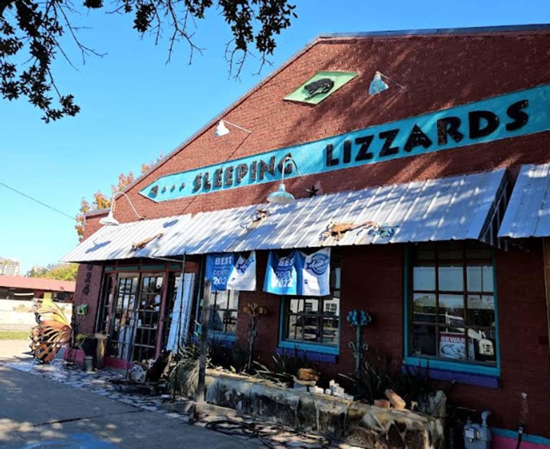 Red brick building with white awning and light blue signage that reads "sleeping lizzards"