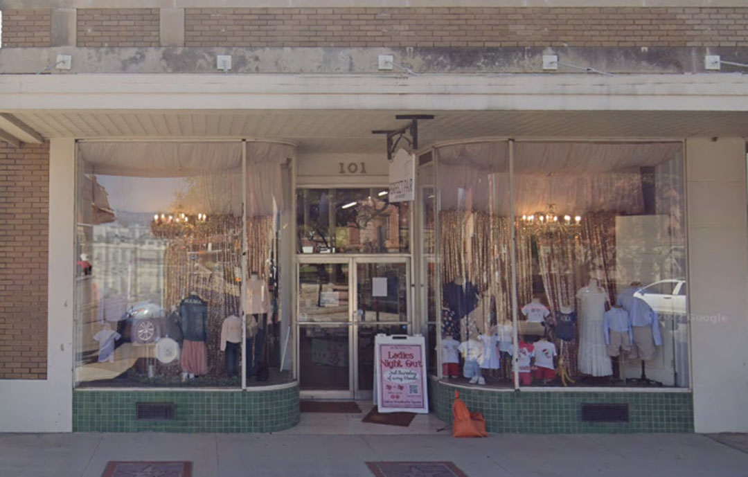 A beige building with large window displays of products at Sweet Peas Boutique