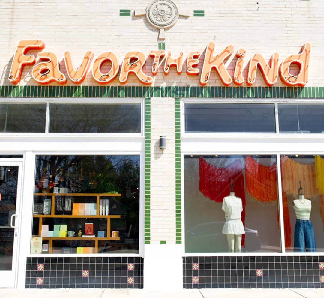A white brick building with neon orange sign that reads "favor the kind"