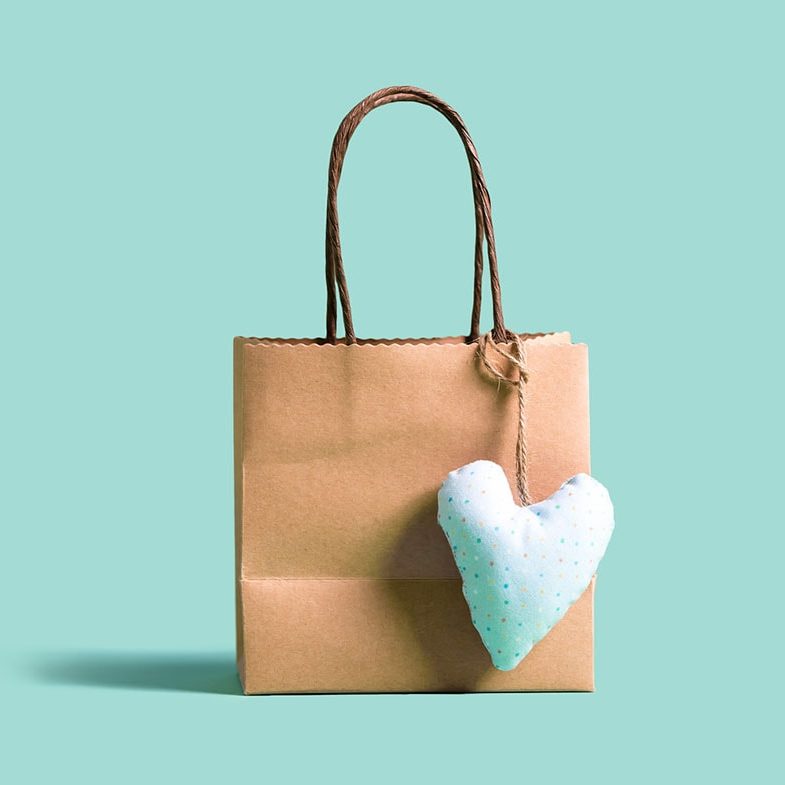 A brown kraft gift bag with a blue felt plush heart tag sits on a blue background.